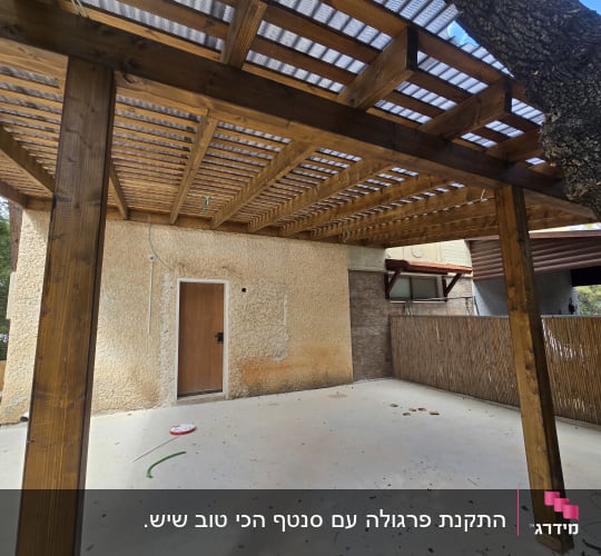 פרגולה מעץ בחצר עם גדר במבוק